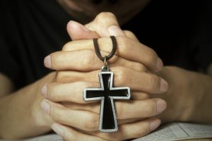 Man praying to God with bible and rosary on his hands